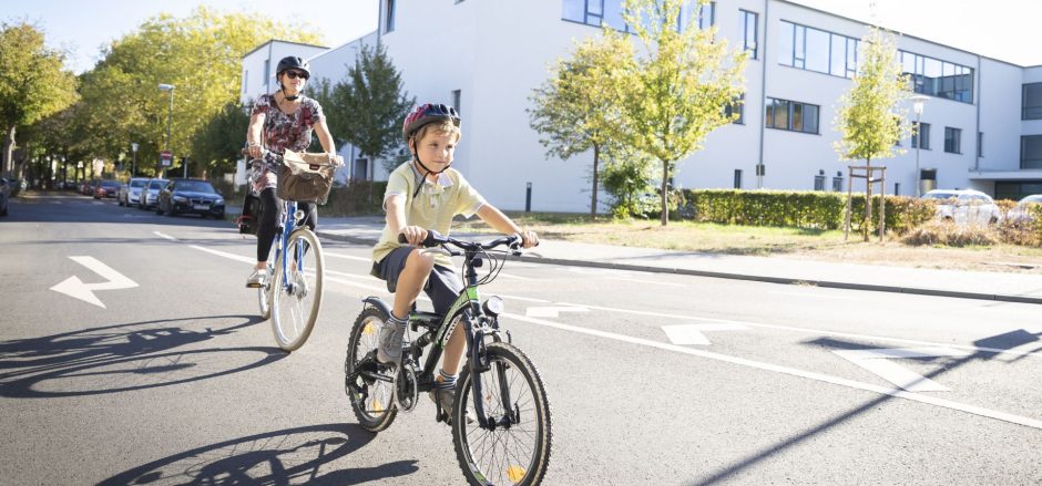 Frau und Kind unterwegs mit Fahrrädern auf der Straße