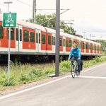 Radfahrer unterwegs auf Radschnellweg parallel zu Bahnschienen