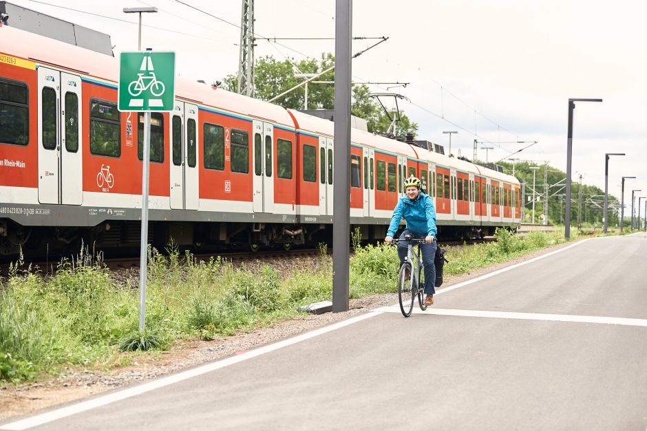 Radfahrer unterwegs auf Radschnellweg parallel zu Bahnschienen
