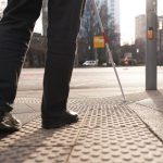 Person mit Blindenstock nutzt die Strukturrillen in Fußgängerwegen