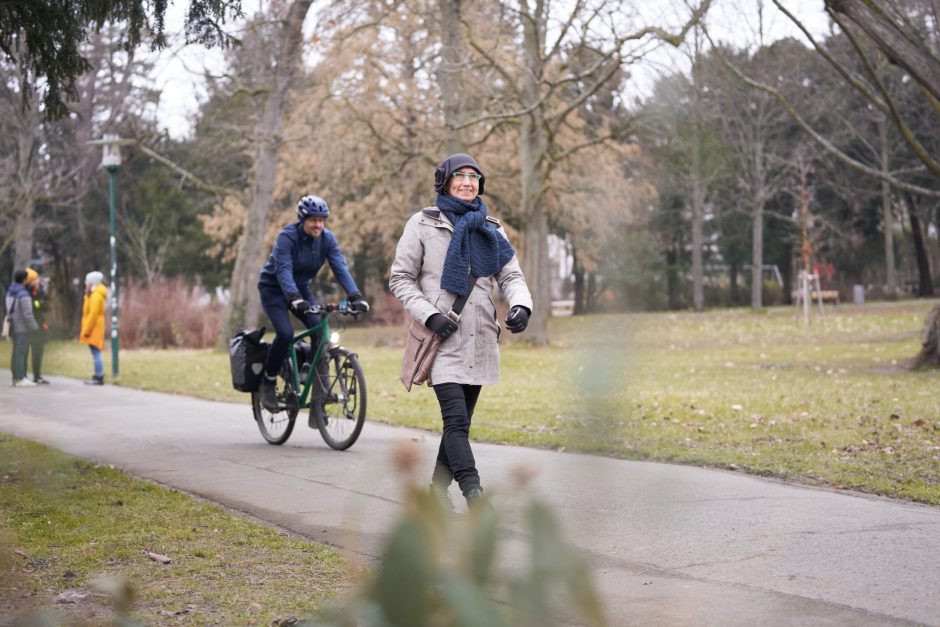 Im Park unterwegs: Frau zu Fuß und Mann auf dem Fahrrad