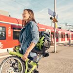Frau mit Klapprad am Bahnhof vor S-Bahn