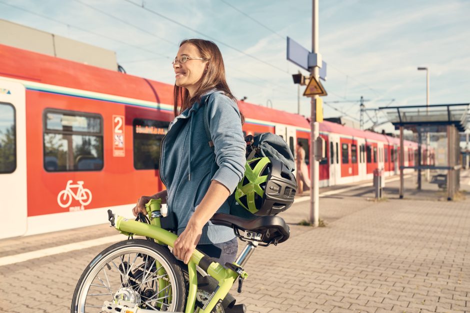 Frau mit Klapprad am Bahnhof vor S-Bahn