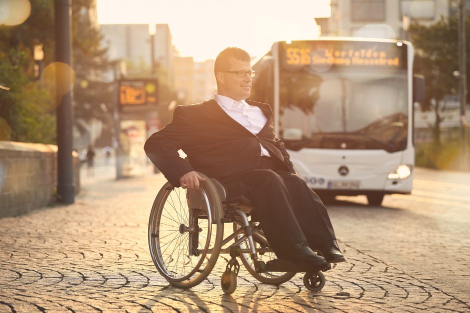 Rollstuhlfahrer an Bushaltestelle