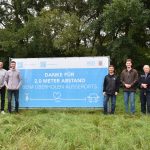 Ein Banner zum Radverkehr "Zwei Meter Abstand" mit Personen links und rechts davon